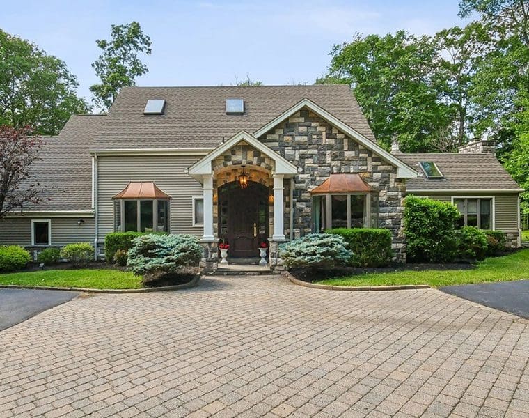 A large brick driveway with a stone house.